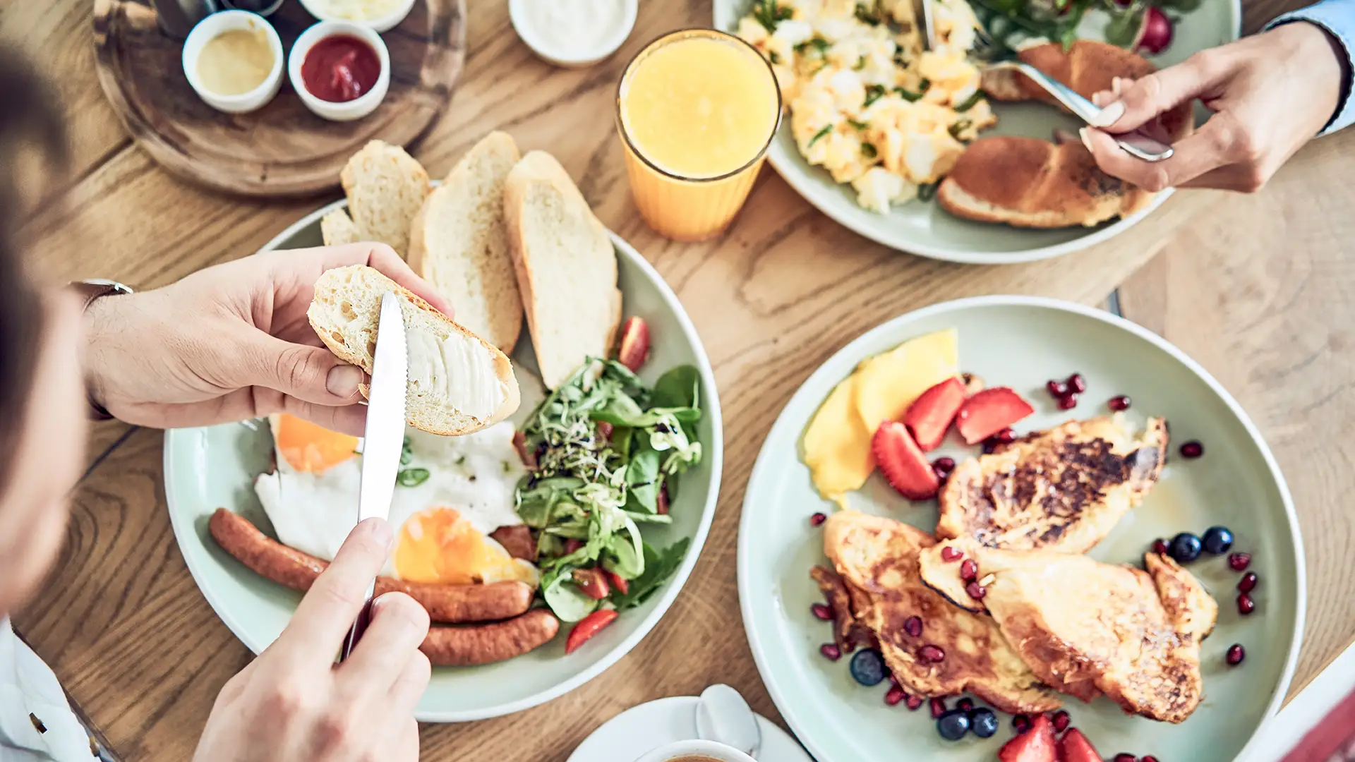 Menschen, die bei einem gemeinsamen Brunch am gedeckten Tisch sitzen