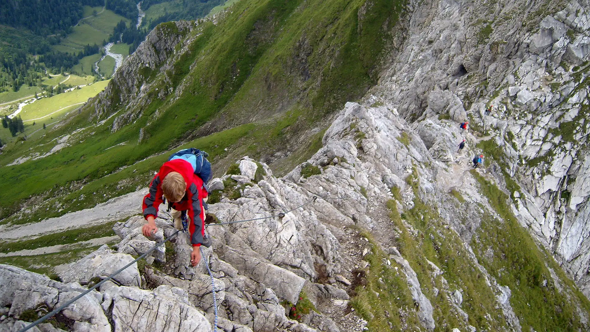 Junger Mann auf dem Aufstieg mittels eine Klettersteigs