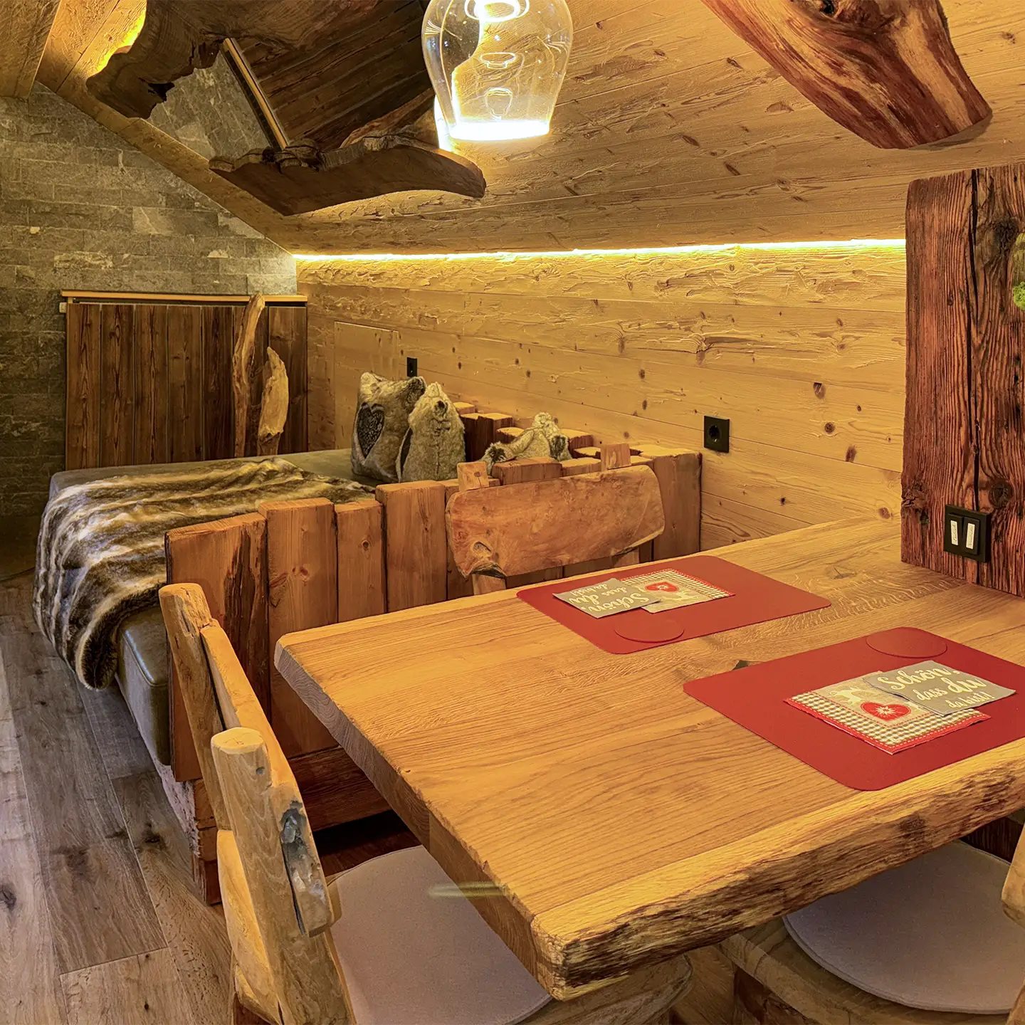 Esstisch aus Holz mit großem Sofa im Hintergrund.