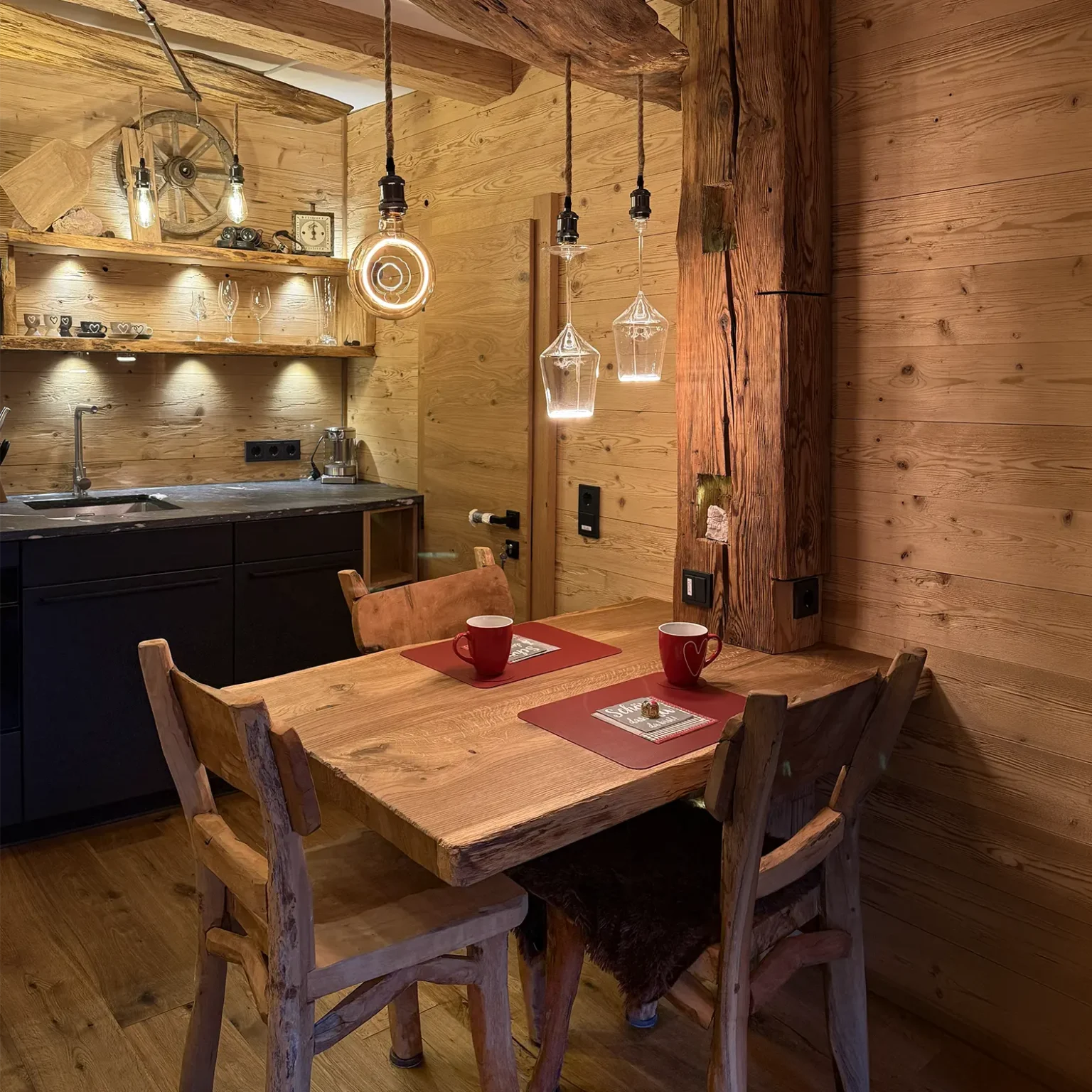 Der Esstisch aus Holz vor der offenen Küche der Wohnung.