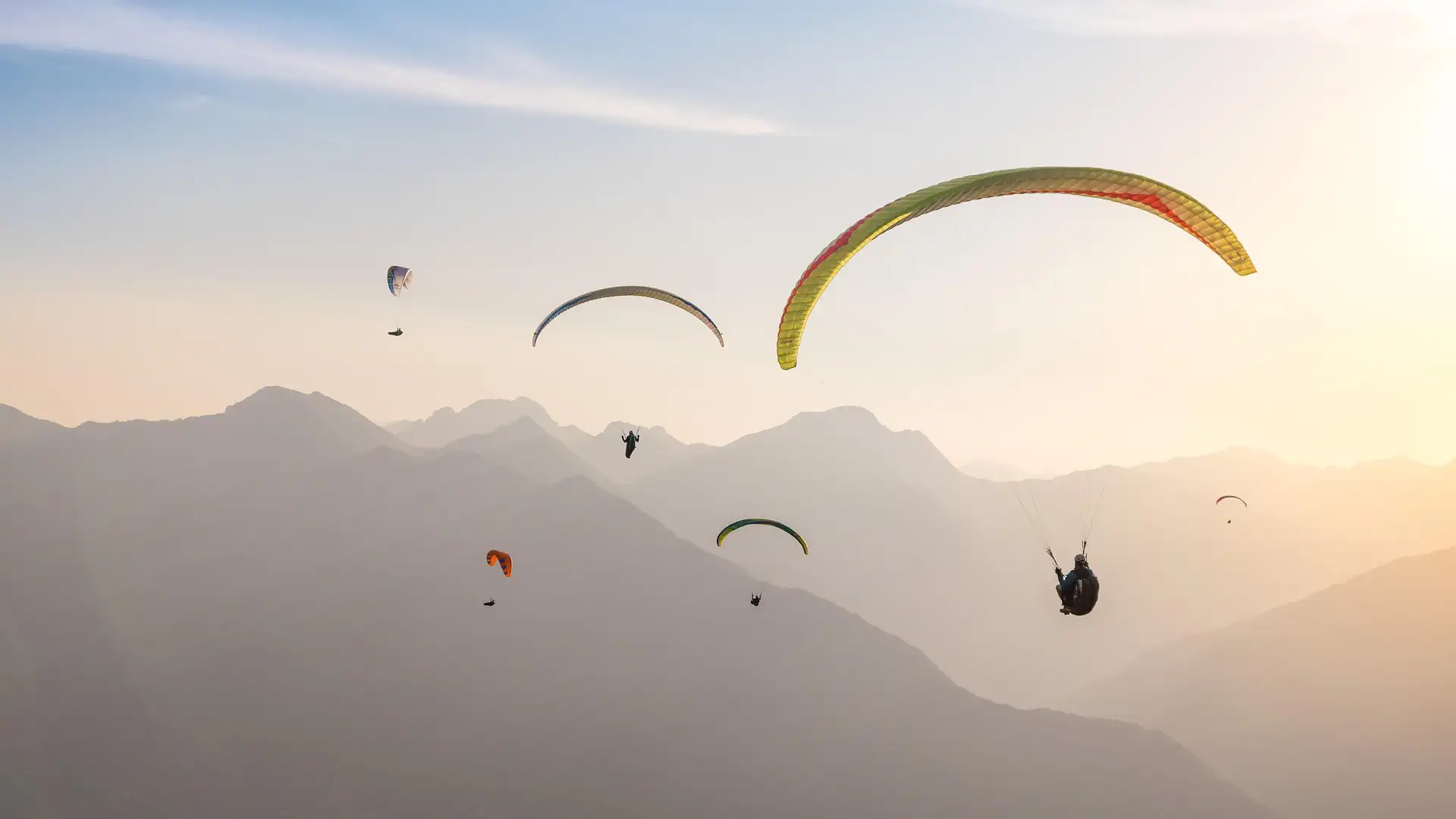 Verschiedene Paraglider am Himmel cor den Bergen